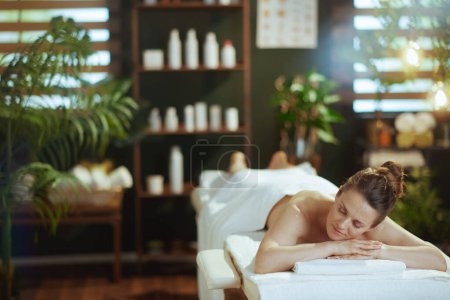 Téléchargez les photos : Temps de santé. moderne détendue femme d'âge moyen dans le salon de spa pose sur la table de massage. - en image libre de droit