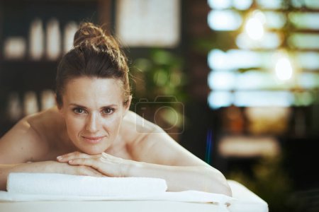 Gesundheitszeit. Entspannte moderne 40-jährige Frau im Wellness-Salon auf Massagetisch liegend.
