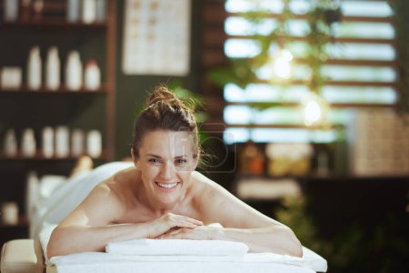 Temps de santé. femme moderne souriante dans un salon de spa posé sur une table de massage.