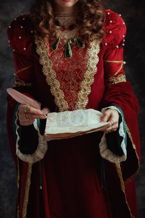 Foto de Primer plano de la reina medieval en vestido rojo con pergamino sobre fondo gris oscuro. - Imagen libre de derechos
