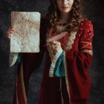 happy medieval queen in red dress with parchment and crown on dark gray background.