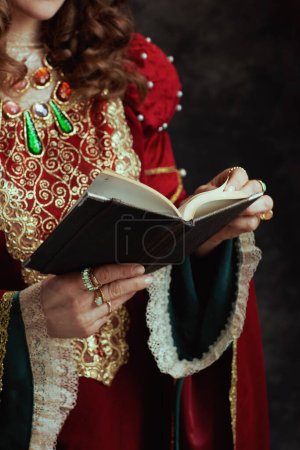 Photo for Closeup on medieval queen in red dress with book on dark gray background. - Royalty Free Image