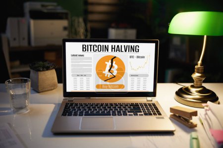 Foto de Escritorio con ordenador portátil con pantalla bitcoin a la mitad por la noche en la oficina moderna. - Imagen libre de derechos