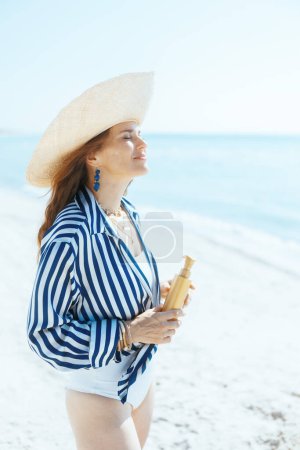 Téléchargez les photos : Souriant femme élégante sur le littoral avec spf. - en image libre de droit