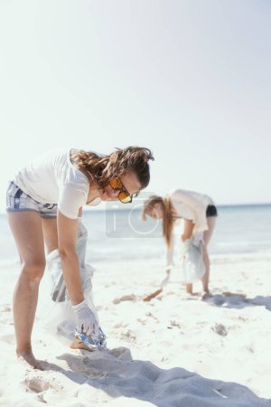 Photo for Smiling eco activists on the beach with trash bags collecting waste. - Royalty Free Image
