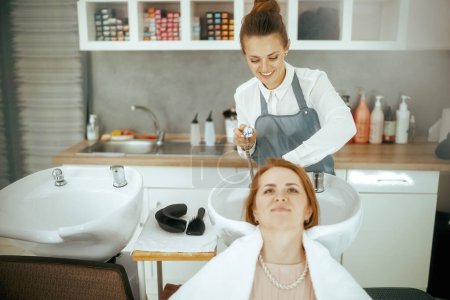 Foto de Mujer peluquería trabajador en estudio de pelo moderno con el cliente de lavado de cabello. - Imagen libre de derechos