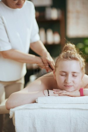 Téléchargez les photos : Temps de santé. Massothérapeute médicale féminine dans une armoire de massage avec un client adolescent faisant un massage sur une table de massage. - en image libre de droit