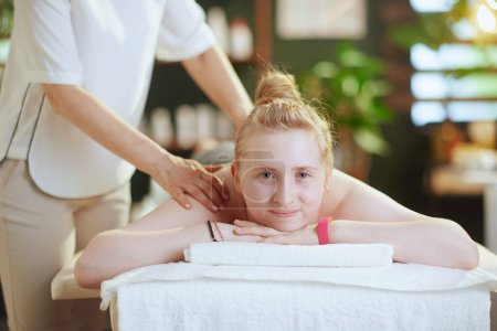 Foto de Tiempo de atención médica. terapeuta de masaje médico femenino en gabinete de masaje con cliente adolescente haciendo masaje en mesa de masaje. - Imagen libre de derechos