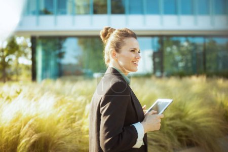 happy modern business woman in business district in black jacket with digital tablet.