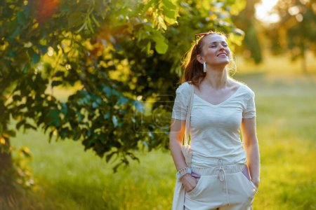 Sommerzeit. lächelnde elegante Frau im weißen Hemd genießt draußen in der Natur.