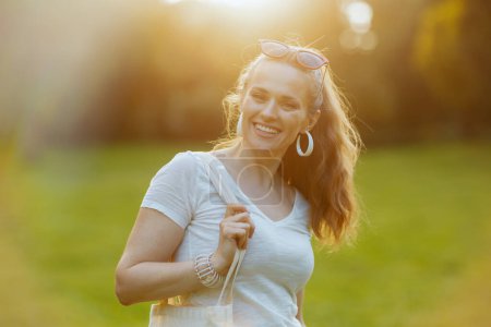 Sommerzeit. Porträt einer glücklichen Trendfrau im weißen Hemd auf der Wiese im Freien.