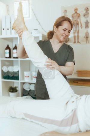 Photo for Healthcare time. happy female medical massage therapist in massage cabinet with client doing checkup. - Royalty Free Image