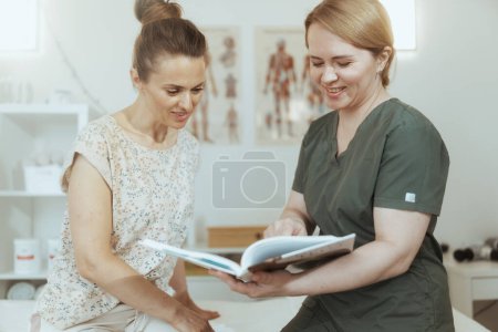 Foto de Tiempo de atención médica. terapeuta de masaje médico femenino sonriente en gabinete de masaje con cliente. - Imagen libre de derechos