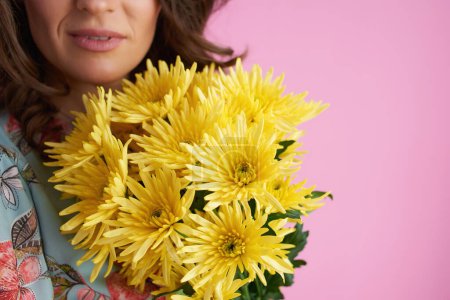 Foto de Primer plano de la mujer con flores de crisantemos amarillos aislados en rosa. - Imagen libre de derechos