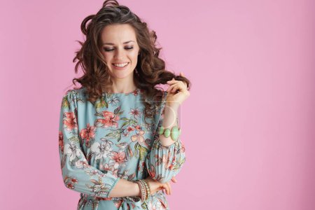 Photo for Smiling modern woman in floral dress with bracelets against pink background. - Royalty Free Image