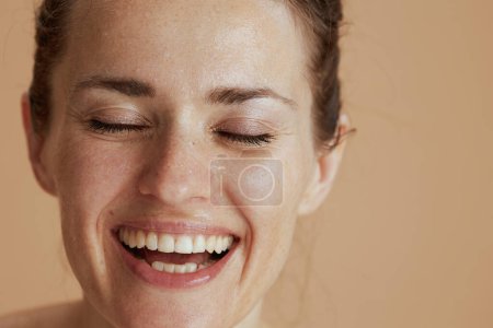 Téléchargez les photos : Gros plan sur heureuse femme moderne avec lavage visage humide isolé sur beige. - en image libre de droit