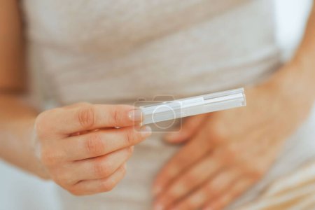 Téléchargez les photos : Gros plan sur une jeune femme tenant un test de grossesse - en image libre de droit