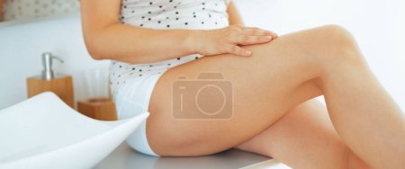Téléchargez les photos : Gros plan sur la jeune femme vérifiant la douceur de la peau des jambes - en image libre de droit