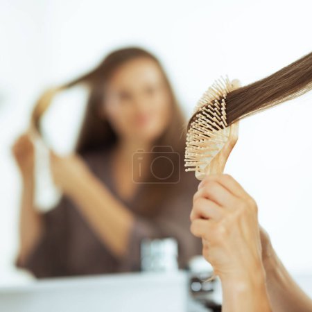 Téléchargez les photos : Jeune femme peigner les cheveux dans la salle de bain. vue arrière - en image libre de droit