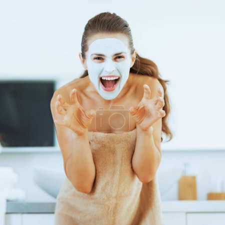 Foto de Mujer joven con máscara cosmética en la cara de miedo - Imagen libre de derechos