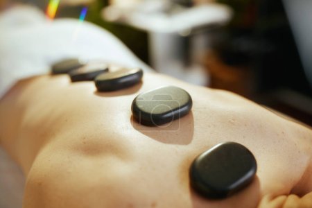 Photo for Healthcare time. Closeup on relaxed woman in massage cabinet having hot stone massage and laying on massage table. - Royalty Free Image
