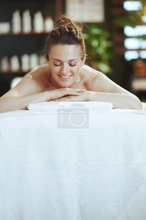 Téléchargez les photos : Temps de santé. souriant moderne femelle dans l'armoire de massage pose sur la table de massage. - en image libre de droit
