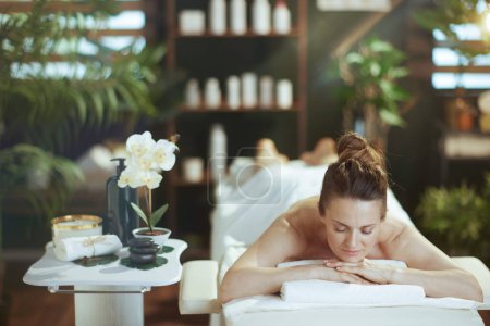 Foto de Tiempo de atención médica. mujer moderna y relajada en el salón de spa acostado en la mesa de masaje. - Imagen libre de derechos