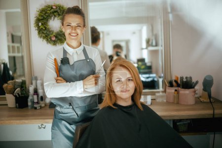 female hairdresser in modern hair studio with scissors and client.