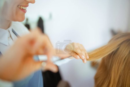 Photo for Closeup on woman hairdresser in modern hair studio with scissors and client cutting hair. - Royalty Free Image