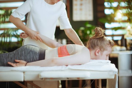 Foto de Tiempo de atención médica. terapeuta de masaje médico femenino en gabinete de masaje con cliente adolescente haciendo masaje. - Imagen libre de derechos