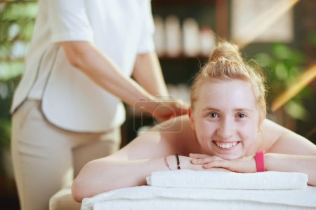 Photo for Healthcare time. female medical massage therapist in massage cabinet with teenage client making massage on massage table. - Royalty Free Image
