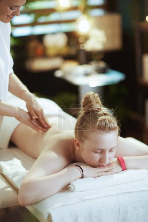 Foto de Tiempo de atención médica. terapeuta de masaje femenino en gabinete de masaje con cliente adolescente haciendo masaje en mesa de masaje. - Imagen libre de derechos