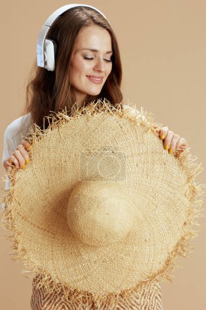 Photo for Beach vacation. smiling stylish female in white blouse and shorts against beige background with headphones. - Royalty Free Image