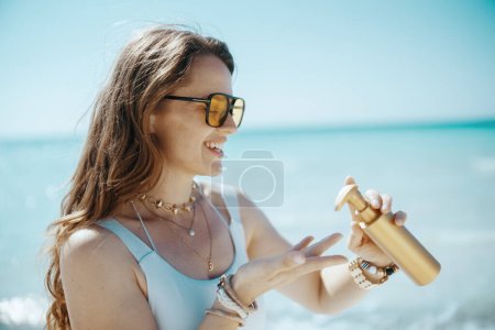 glückliche moderne 40-jährige Frau an der Küste mit Sonnencreme.