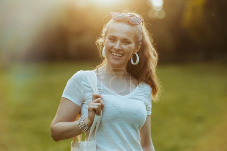 Foto de Hora de verano. Retrato de mujer elegante sonriente en camisa blanca en el prado exterior en la naturaleza. - Imagen libre de derechos