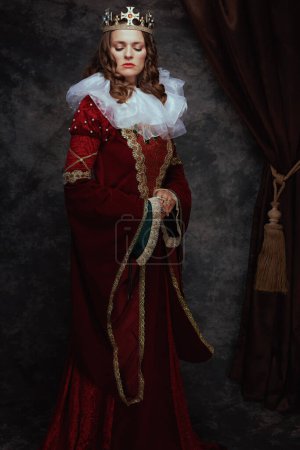 Photo for Full length portrait of medieval queen in red dress with white collar and crown on dark gray background. - Royalty Free Image