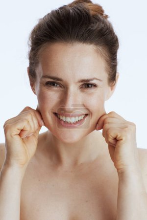 Téléchargez les photos : Sourire jeune femme faire massage facial isolé sur blanc. - en image libre de droit