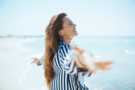 Foto de Smiling modern woman on the beach rejoicing. - Imagen libre de derechos