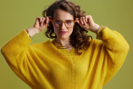 Foto de Retrato de mujer de moda sobre fondo verde en suéter amarillo y gafas. - Imagen libre de derechos