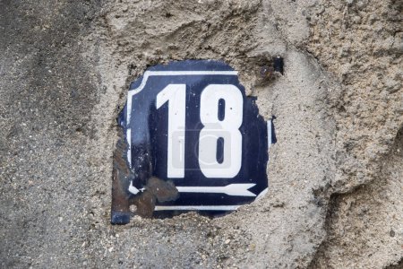Weathered grunge square metal enameled plate of number of street address with number 18