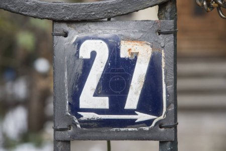 Weathered grunge square metal enameled plate of number of street address with number 27