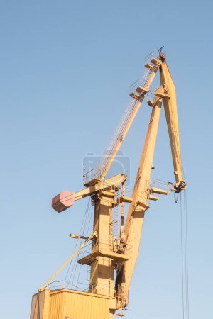Port industrial crane at river sand unloading depot on clear sunny day