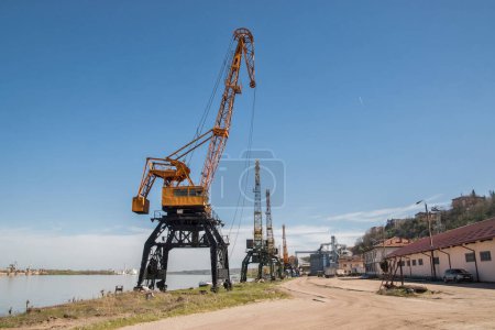 Foto de Grúas industriales portuarias en el depósito de descarga de ríos en un día claro y soleado - Imagen libre de derechos
