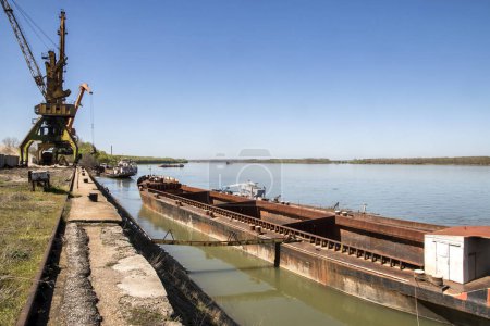 Foto de Barcaza de carga fluvial a granel y grúas industriales en puerto fluvial en día soleado - Imagen libre de derechos