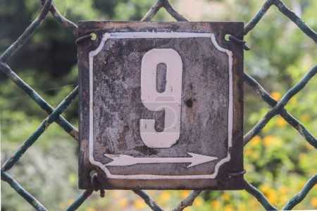 Weathered grunge square metal enameled plate of number of street address with number 9