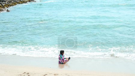Joyeux fille assise sur le bord de l'eau dans la belle plage de San Bartolo au sud de Lima Pérou. Vacances d'été