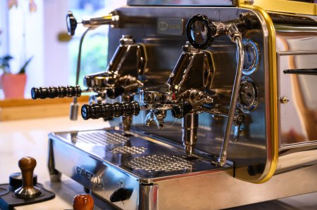 Nahaufnahme einer glänzenden kommerziellen Espressomaschine, die in einem Kaffee-Setting zum Brühen bereit ist