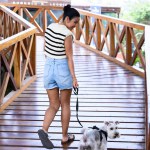 Young woman walking her dog down a quiet path in a downtown urban environment