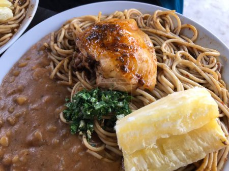 Close-up of traditional west african peanut stew with chicken, spaghetti, and garnishes