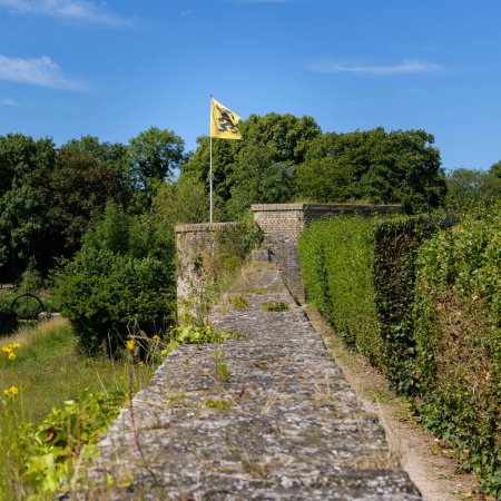 Téléchargez les photos : An old stone wall with flanders flag, summer, blue sky, Bergues (France) - en image libre de droit